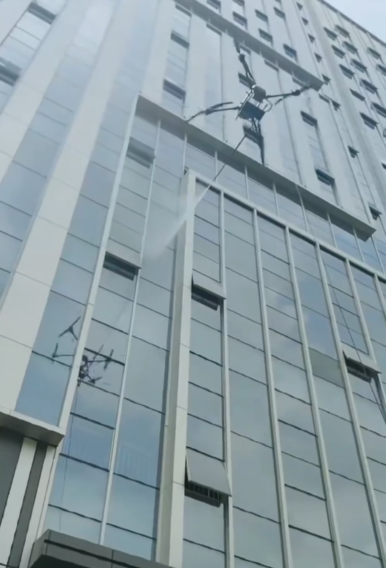 Commercial cleaning drone spraying a glass building facade