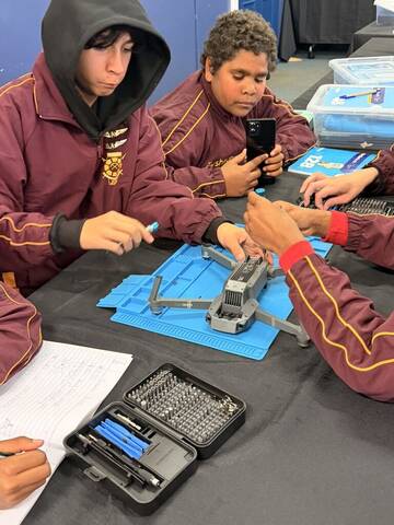 Students in safety glasses working on drone hardware