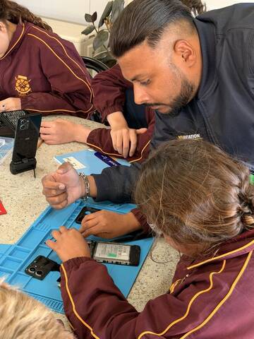 An ACE instructor helping a student mid-repair