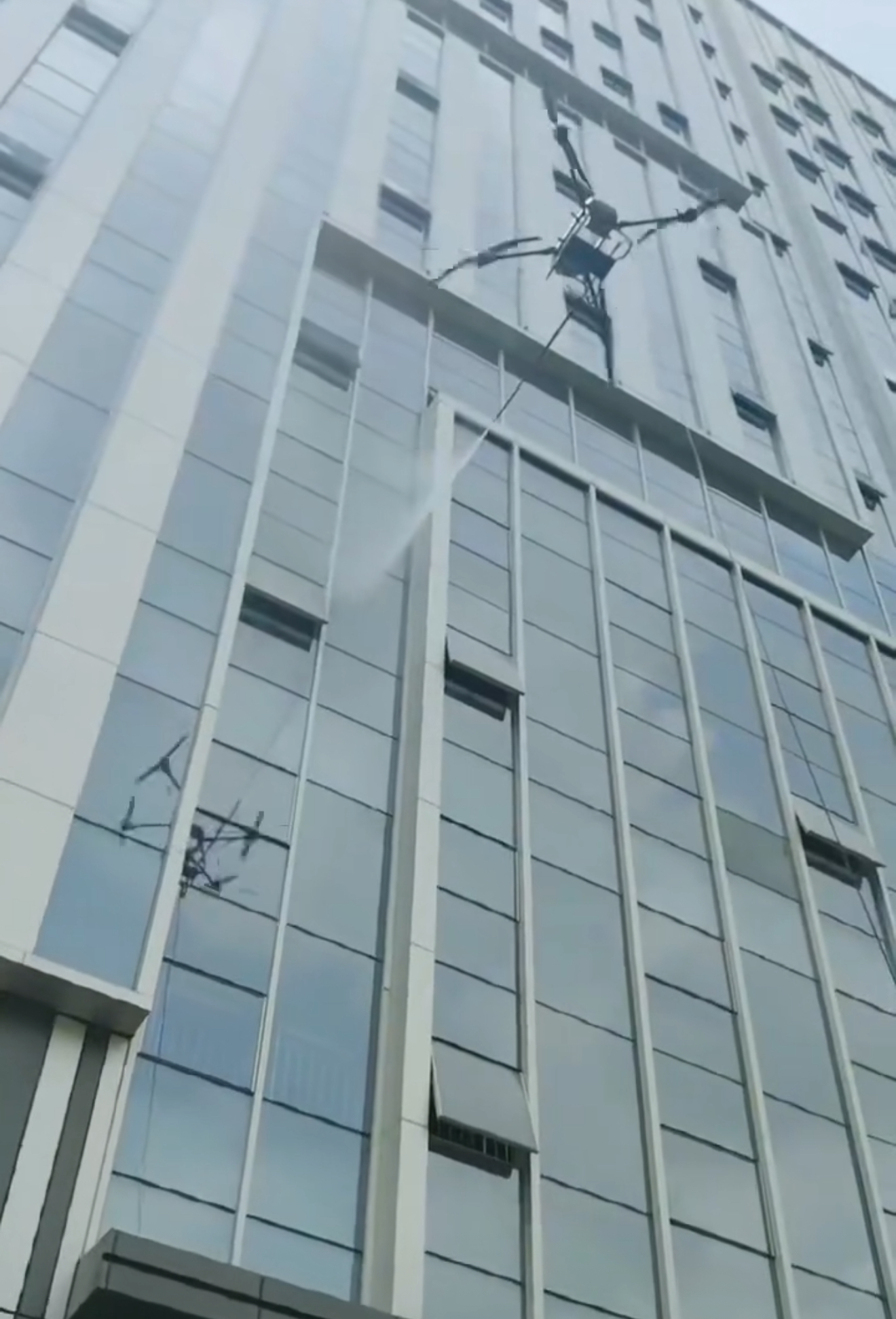 ACE AIR Orion cleaning drone spraying a glass building facade