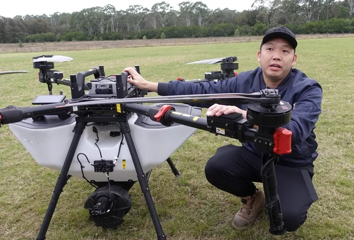 ACE Aviation Director Charles Chow beside an XAG agricultural drone in the field