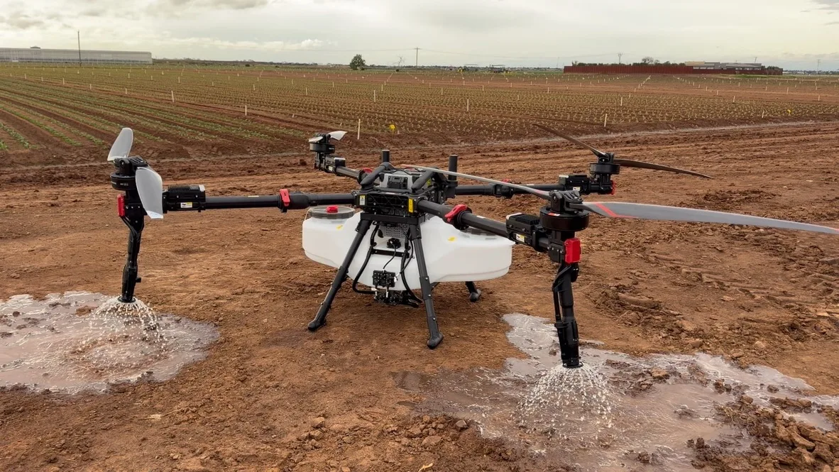 An XAG agricultural drone demonstrating its spray system in the field
